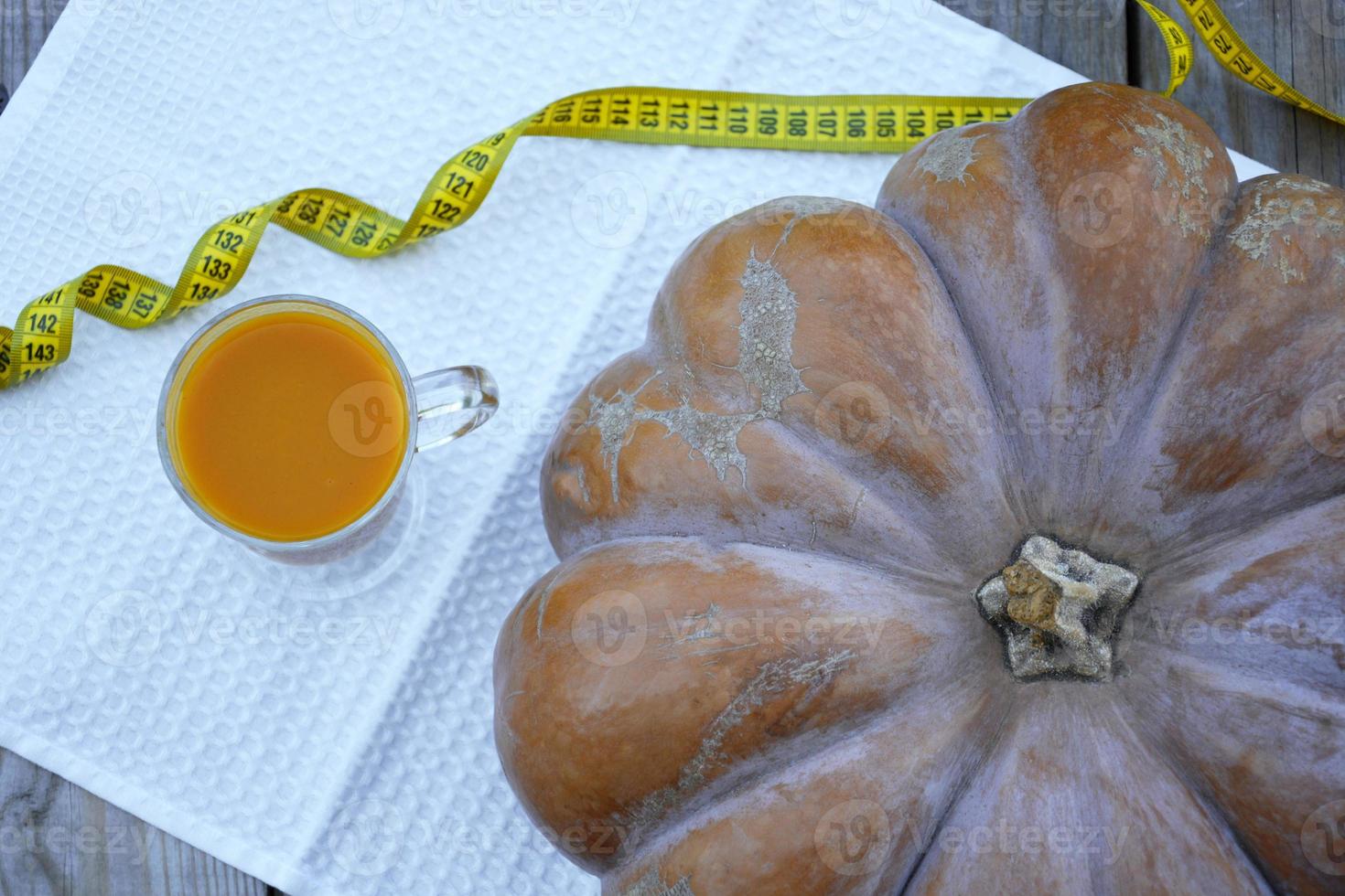 Pumpkin on a wooden background and a glass of pumpkin juice. photo