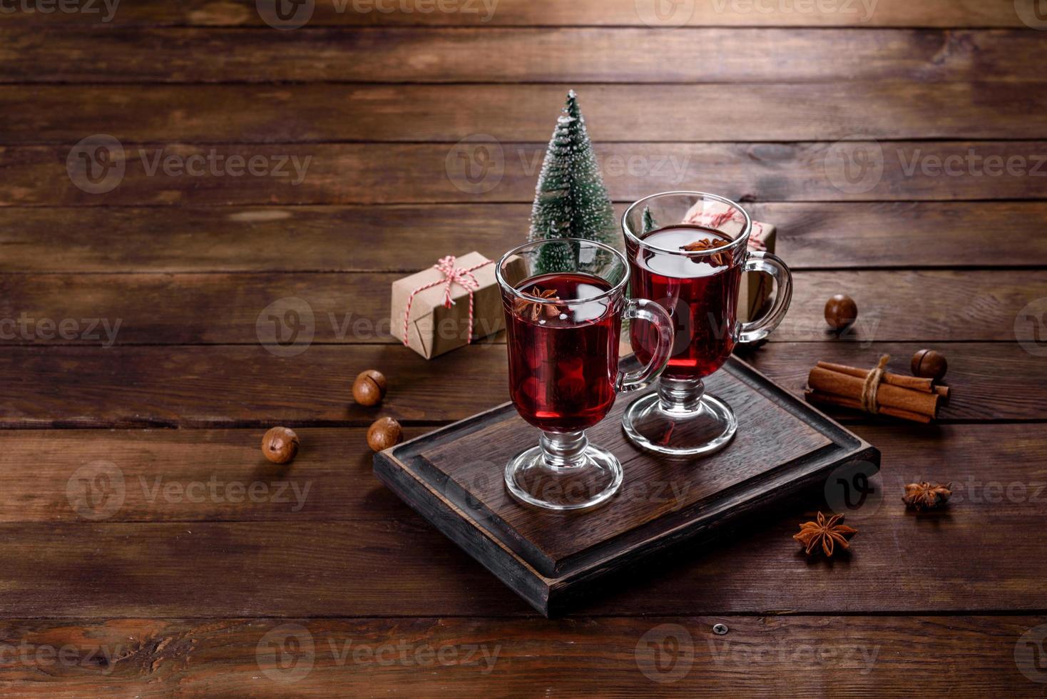 Navidad vino tinto caliente con especias y frutas sobre una mesa oscura. foto