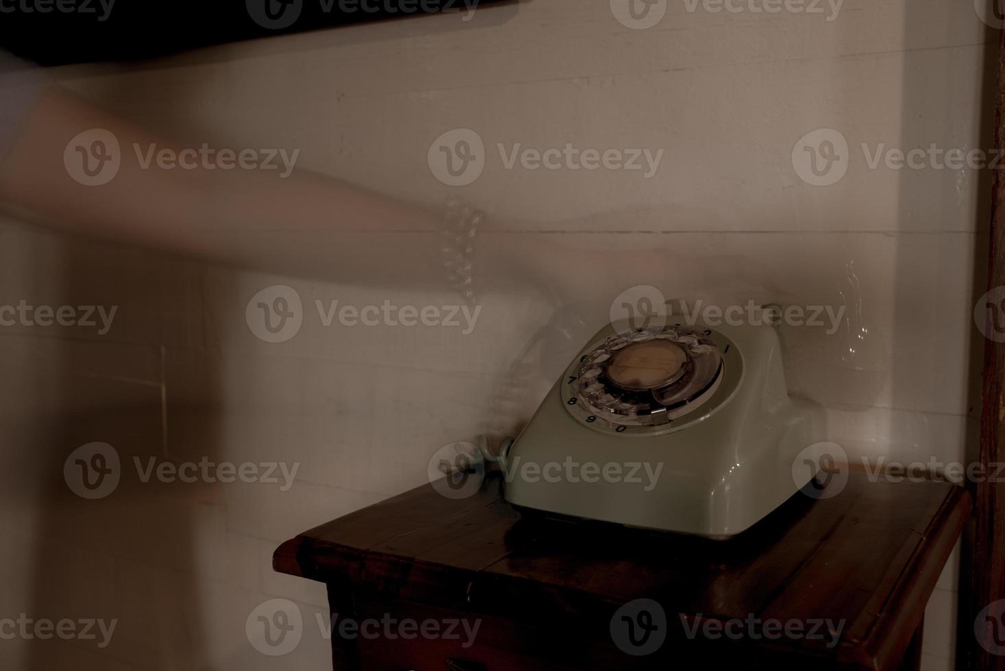 Mano de fantasma sosteniendo auriculares de teléfono retro en casa antigua foto