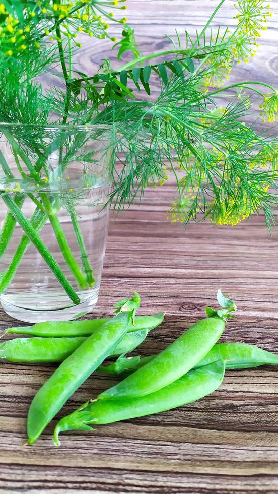 Green peas close-up on a wooden table. Pea and dill leaves in a jar. photo