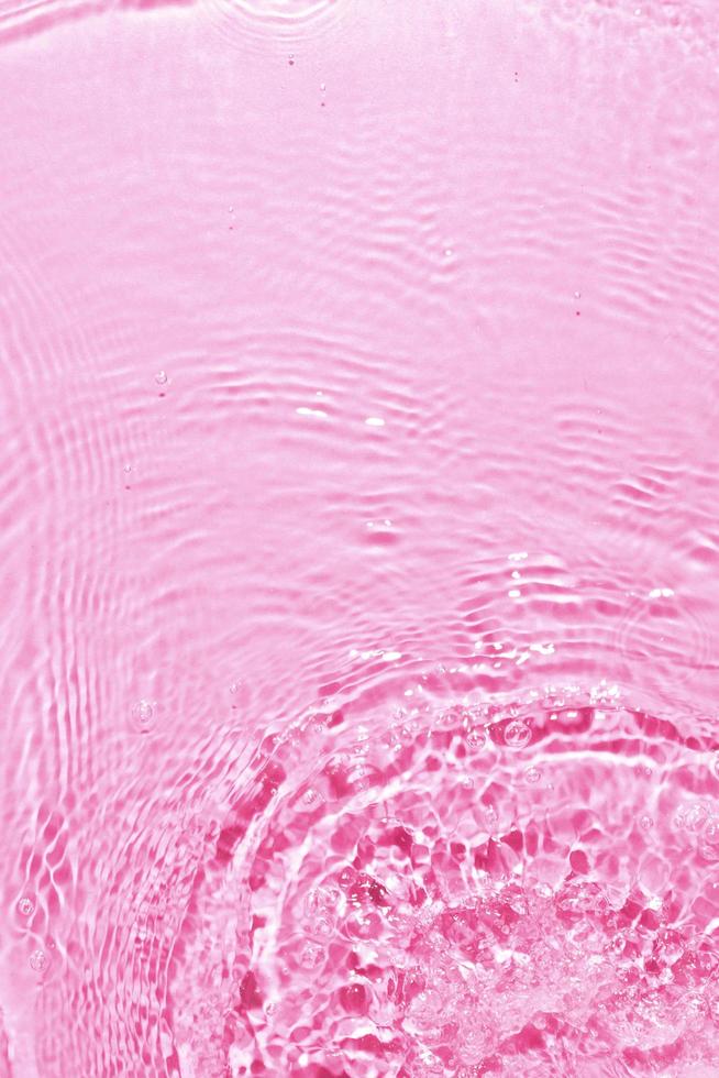Textura de salpicaduras de agua limpia sobre fondo rosa foto