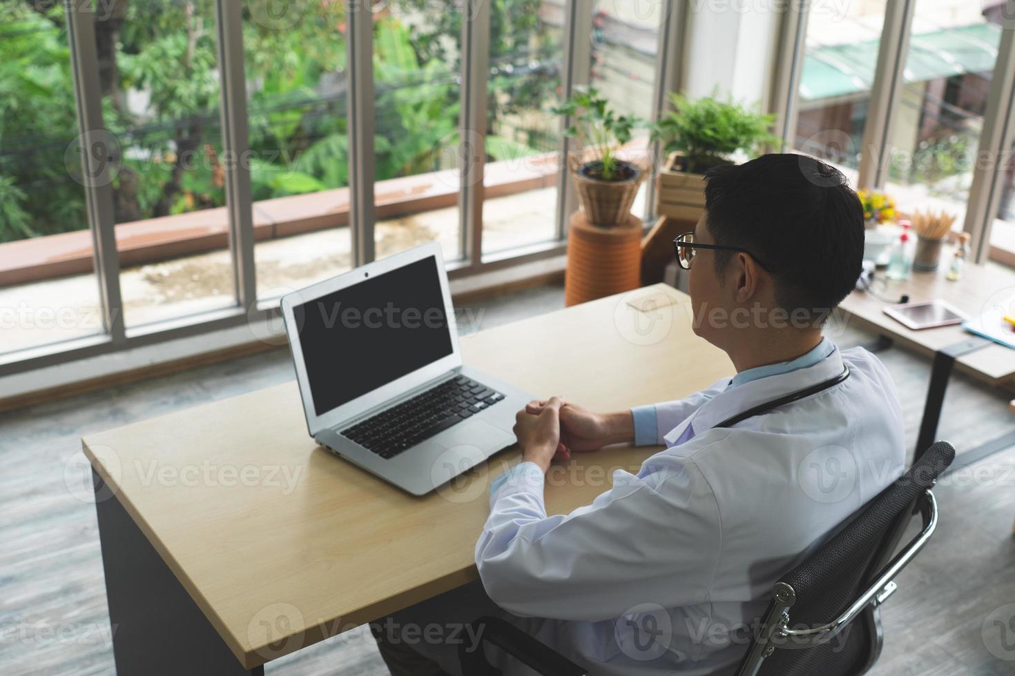 Young Asian doctor working with computer in hospital office photo