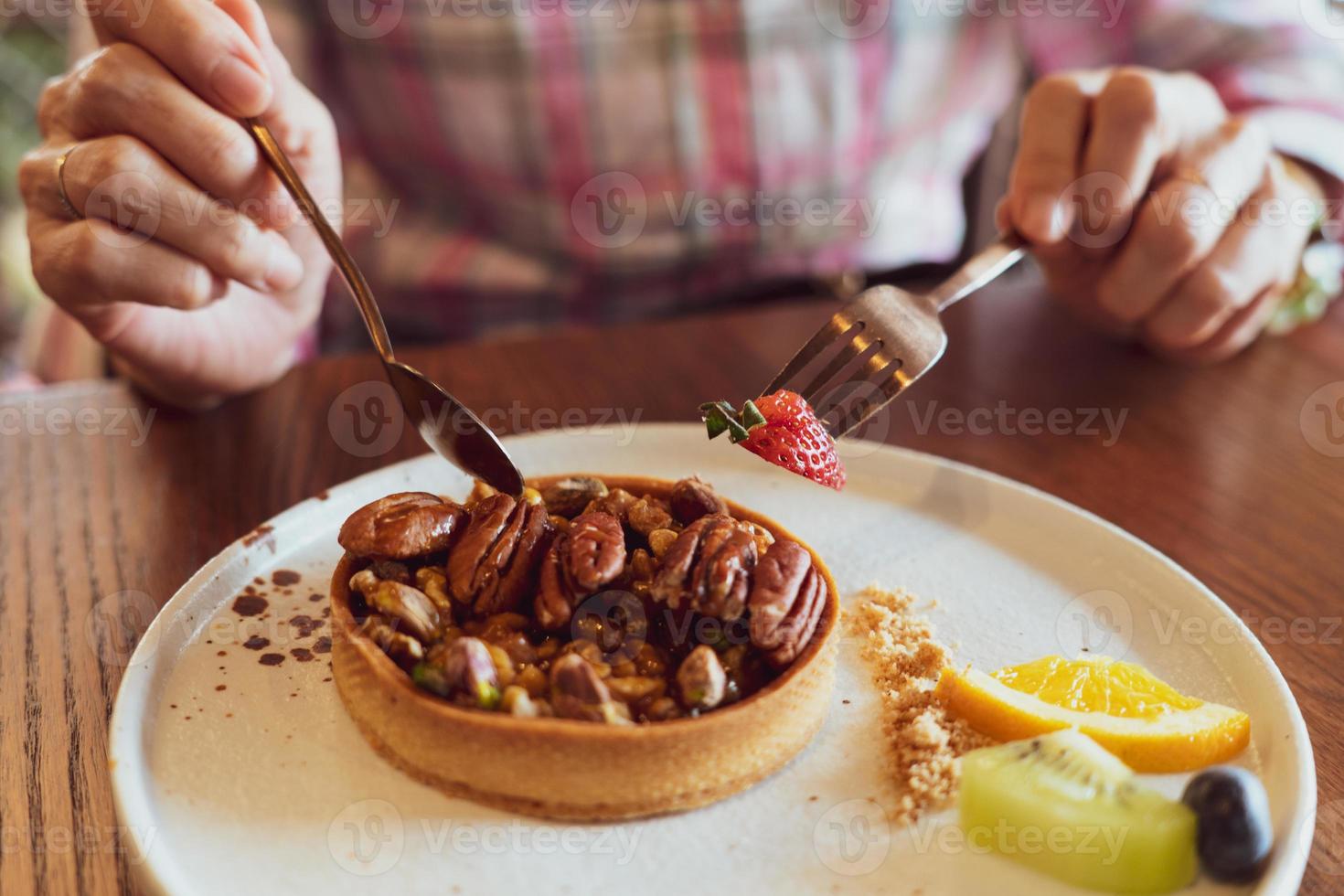 Mujer con tenedor y cuchara para comer pastel de caramelo de maní foto