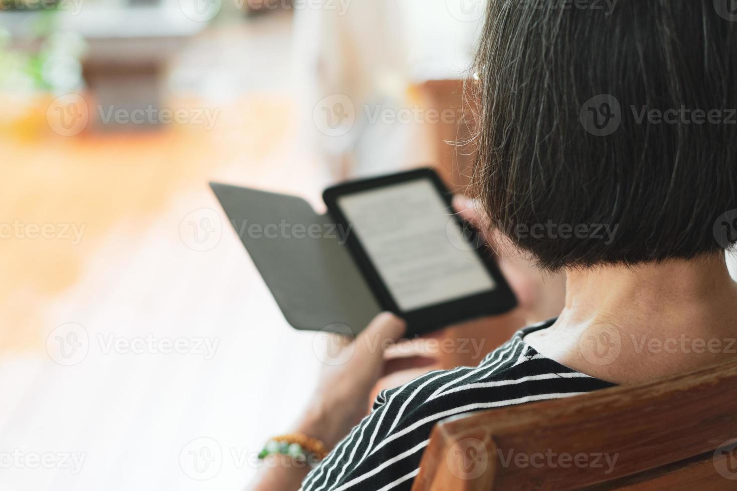 Senior mujer asiática leyendo ebook en casa foto