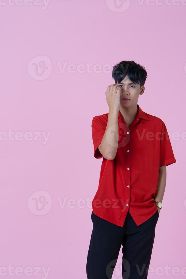 Young handsome hipster Asian man standing on the pink background photo