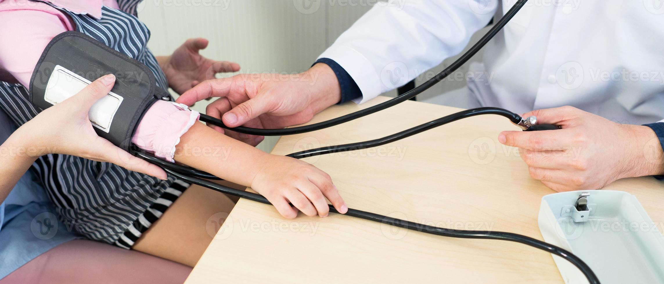 Médico con esfigmomanómetro para medir la presión arterial de la niña. foto