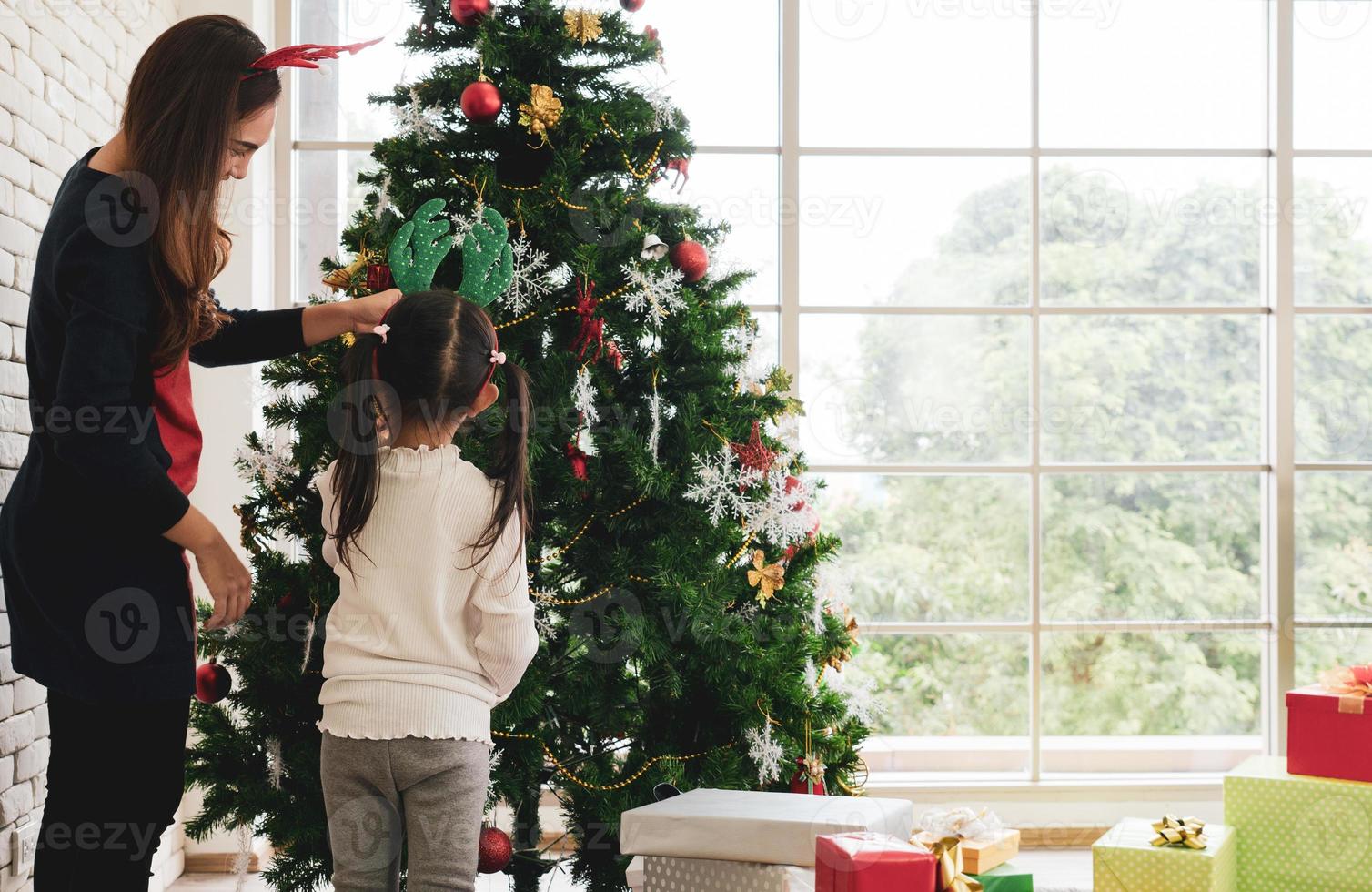 madre e hijo asiáticos decoran juntos el árbol de navidad foto