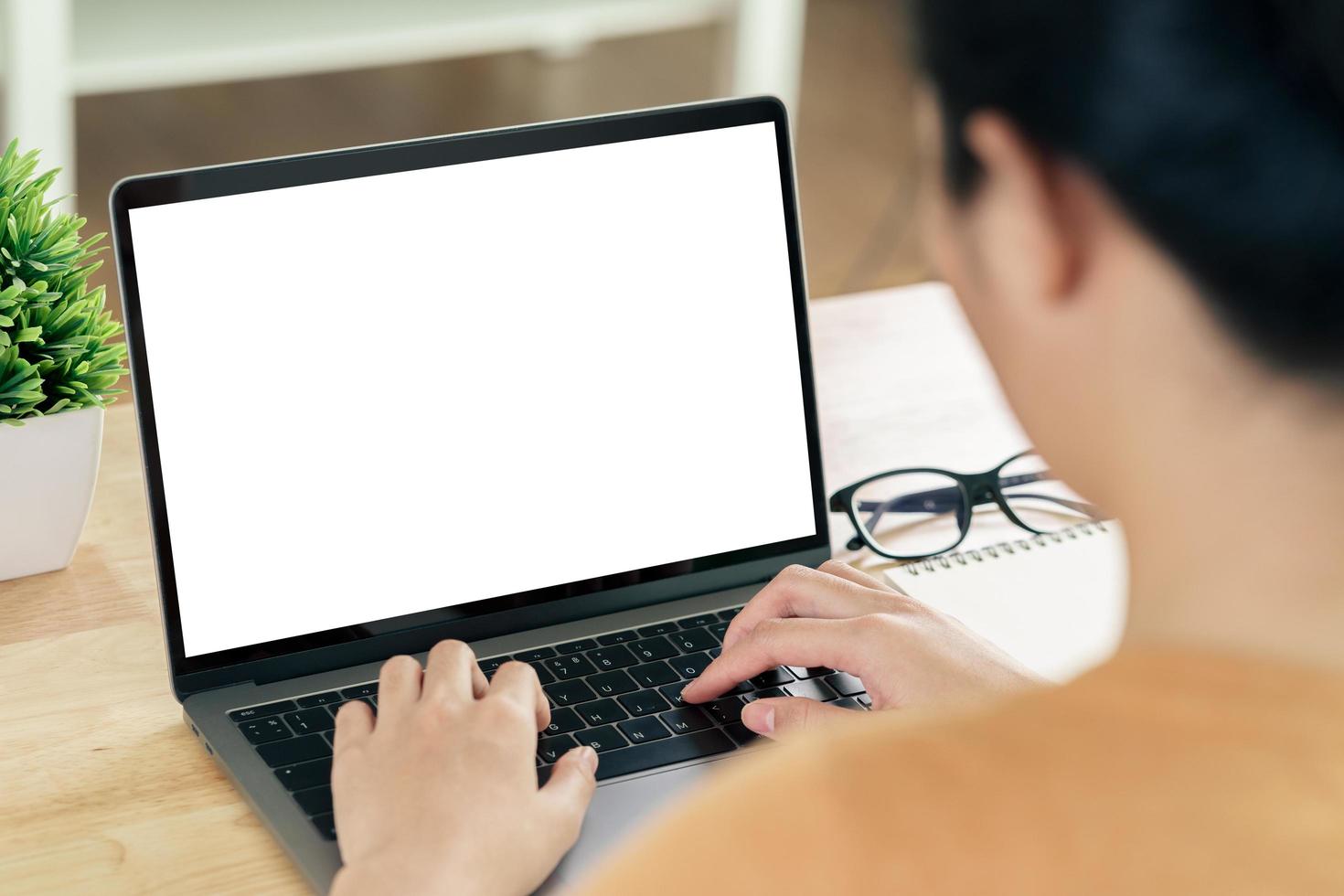 Woman typing laptop keyboard with white blank screen on the table photo