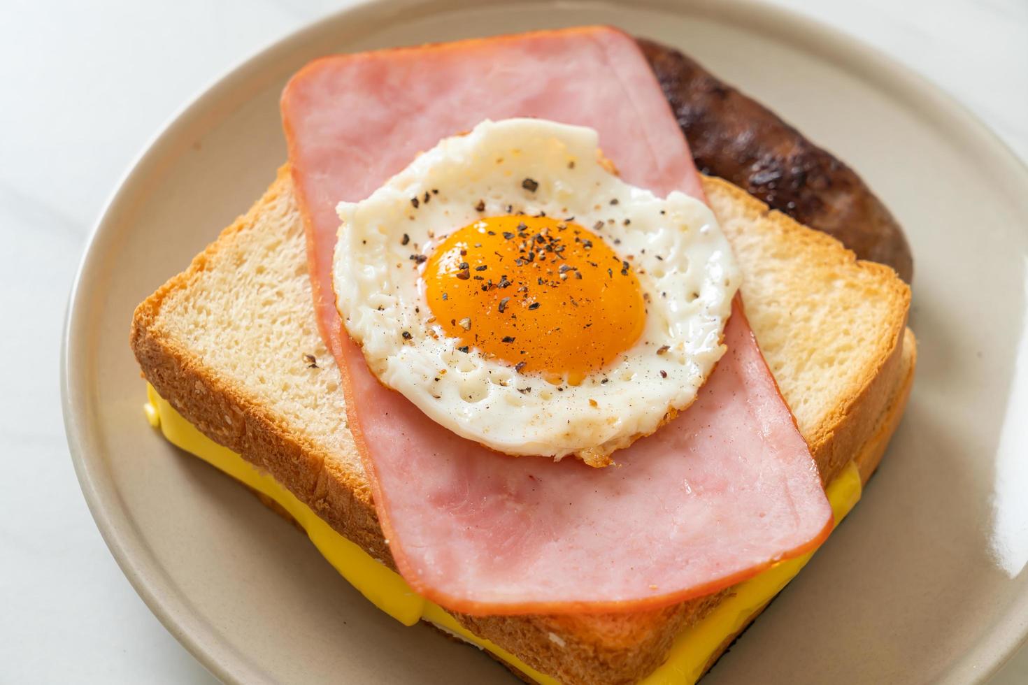 Bread toasted cheese topped ham and fried egg with pork sausage photo