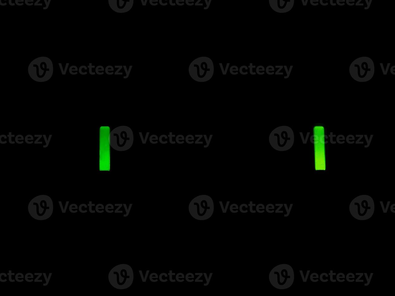 Two green led lights over black background photo