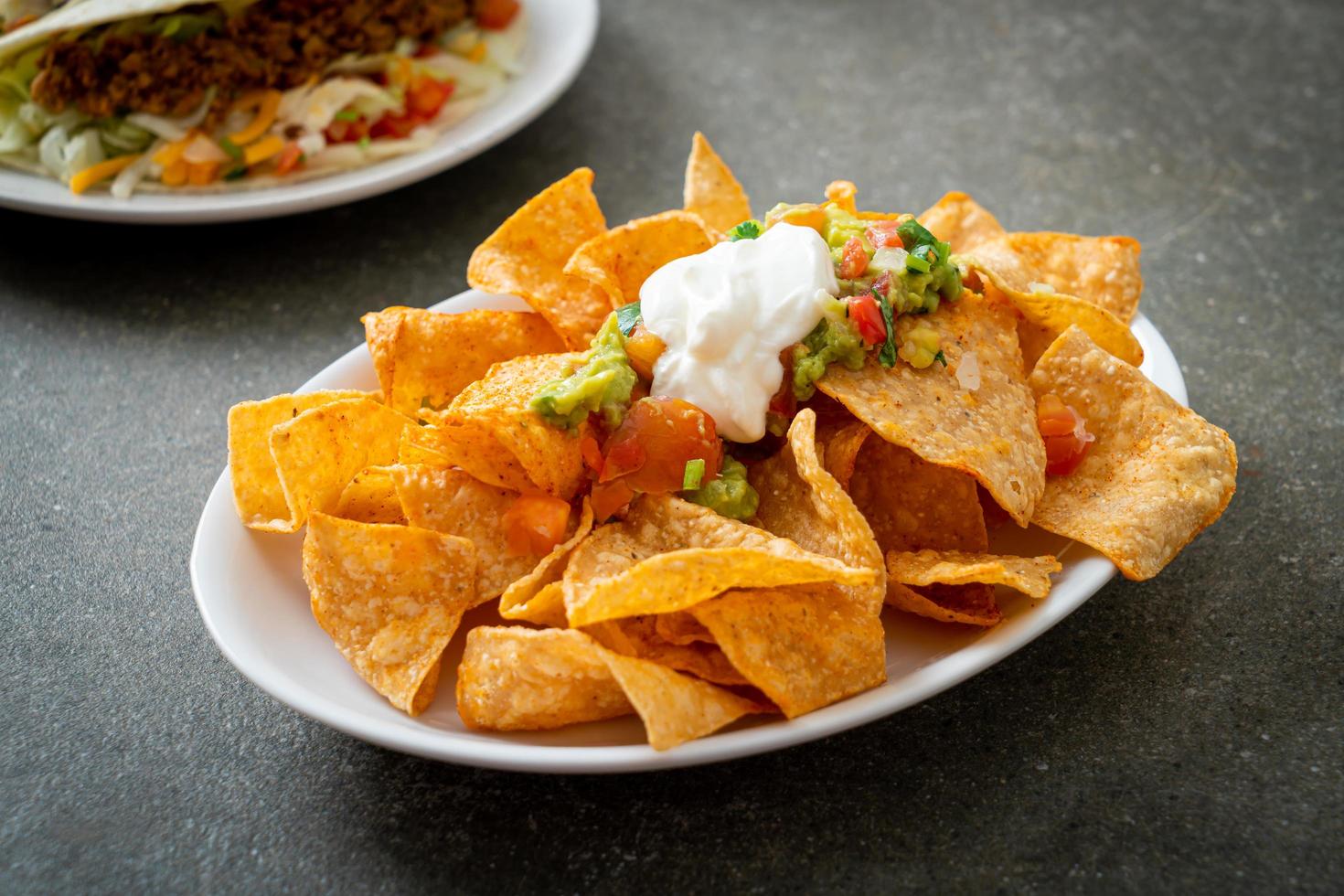 Nachos tortilla chips with jalapeno, guacamole, tomatoes salsa and dip photo