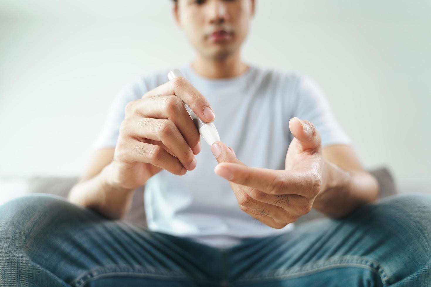 Man use lancet on finger for check blood sugar level by glucose meter photo