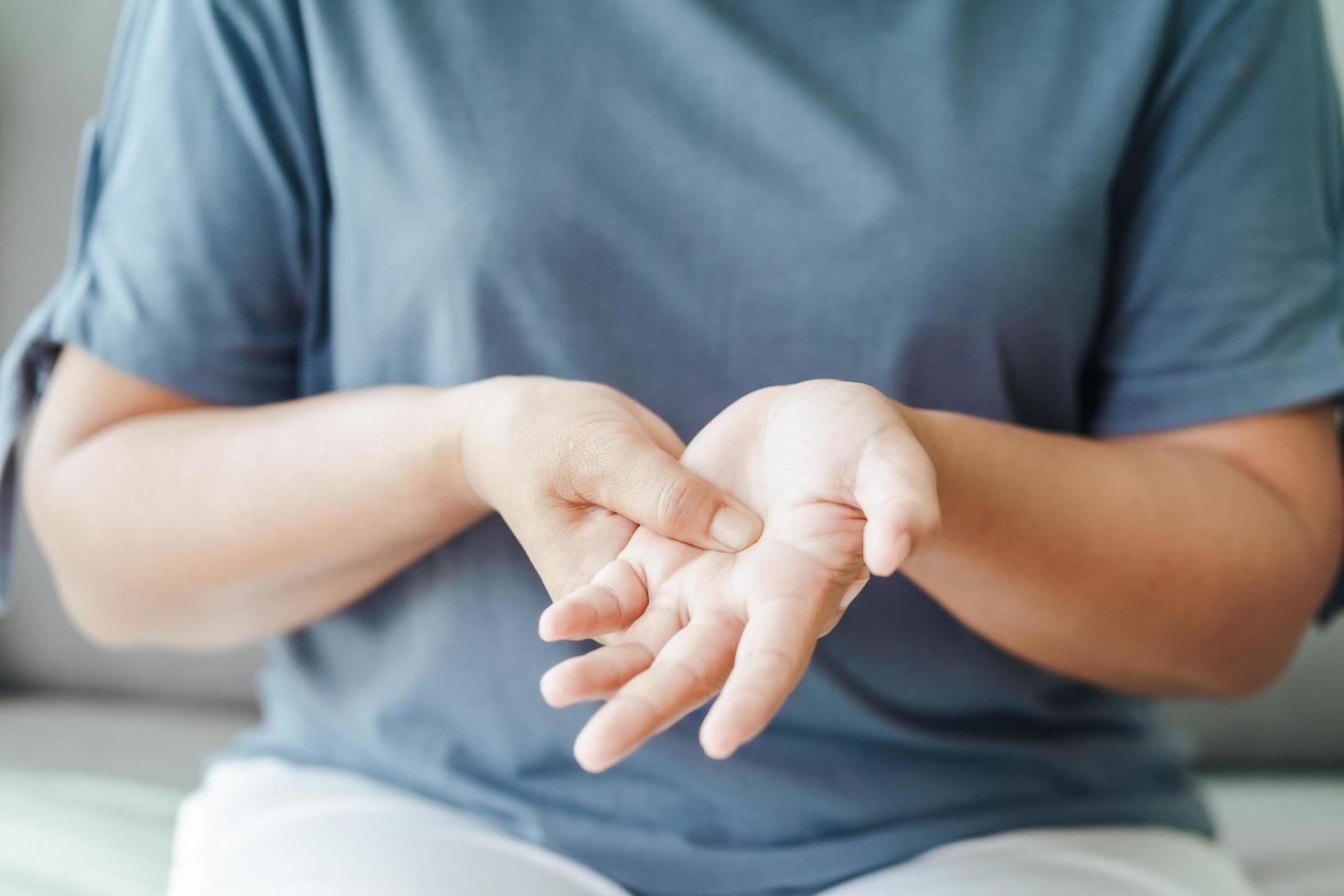 Woman sitting on sofa holds her wrist photo