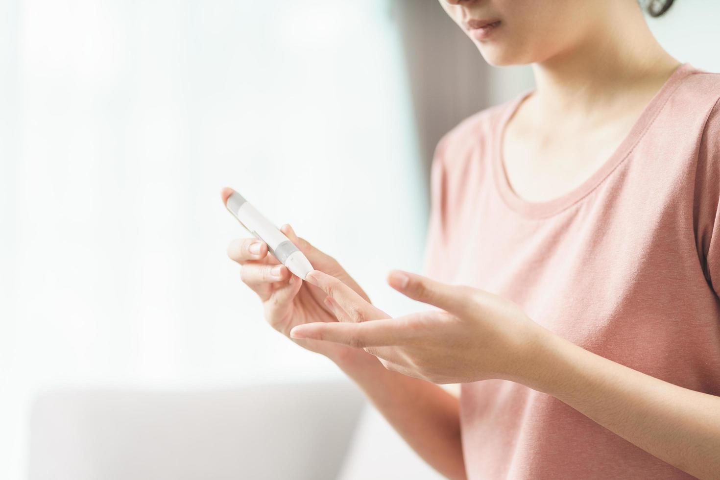 Woman uses lancet on finger for check blood sugar level by glucosemeter photo