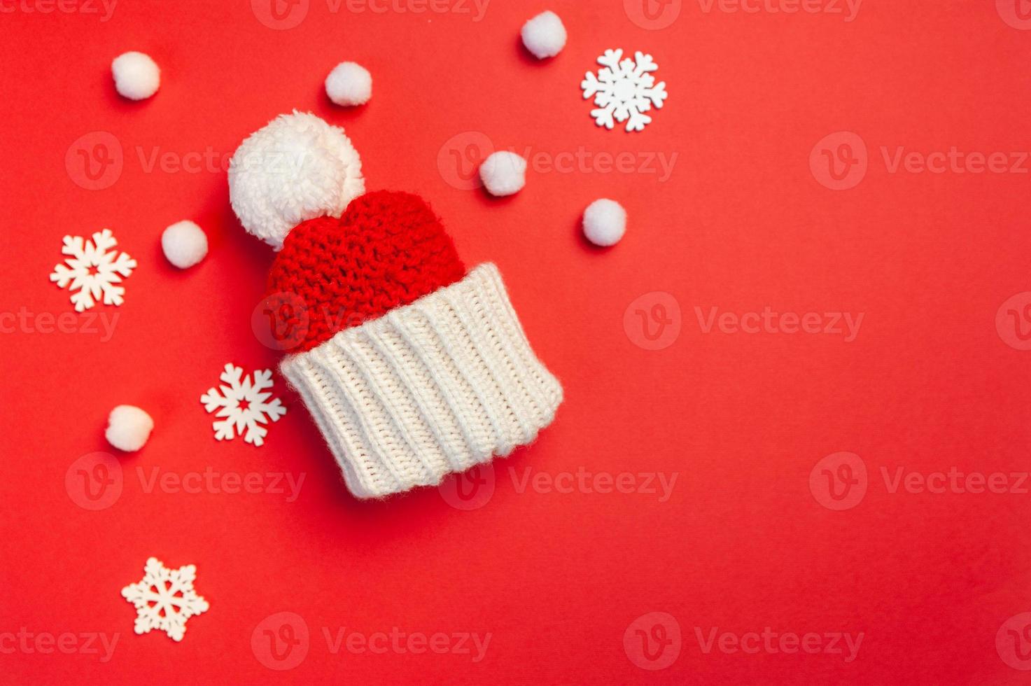 Tarjeta de felicitación de Navidad con sombrero rojo y copos de nieve sobre fondo rojo. foto