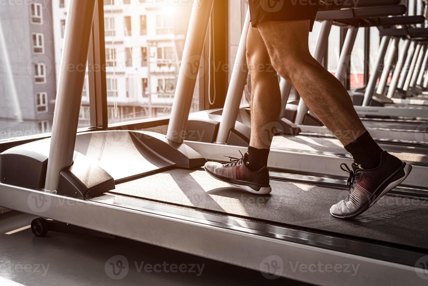 Close up of sport man running on treadmill in fitness gym photo