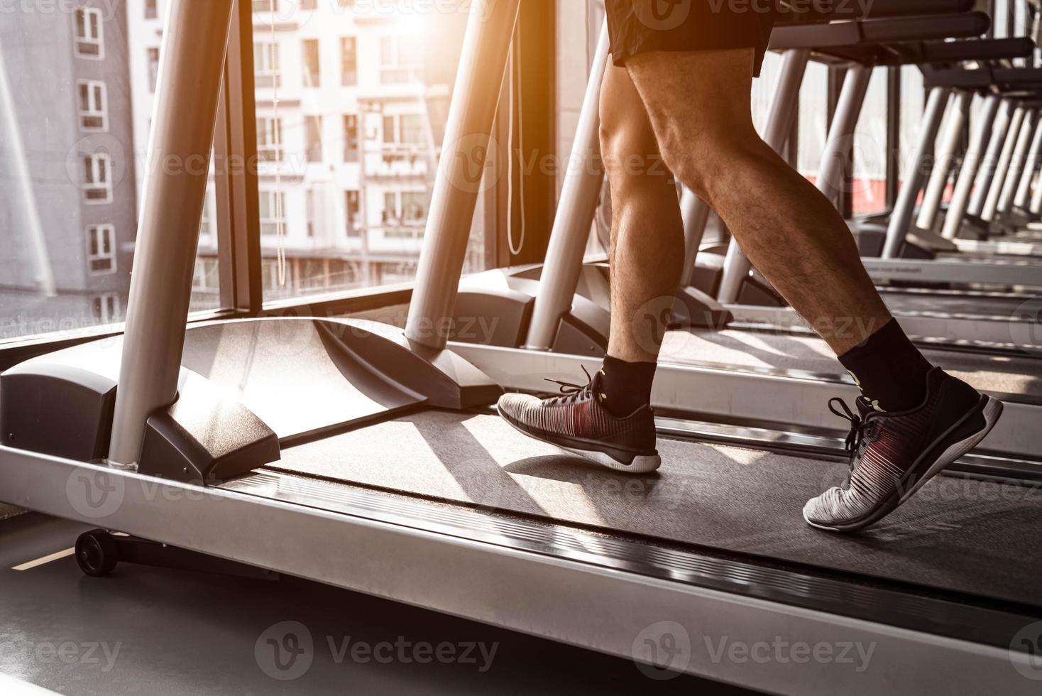 Cerca del deporte hombre corriendo en cinta en el gimnasio foto