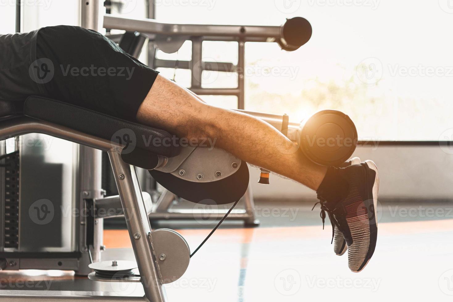Close up of sport man stretching and lifting weight by two legs photo