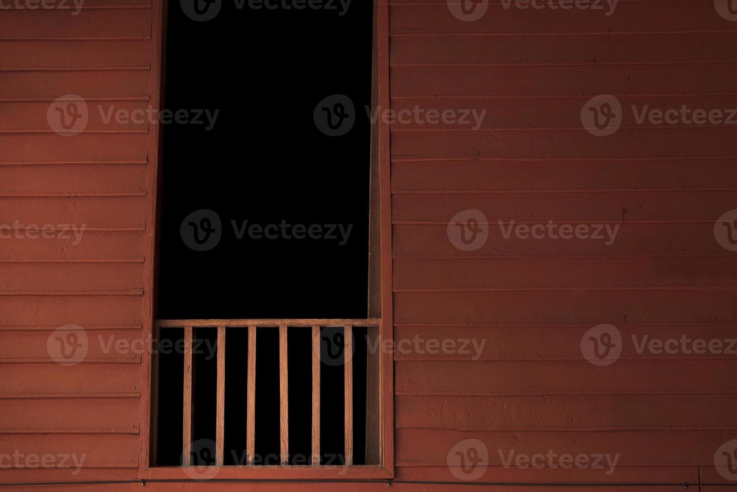 Balcón de madera con cuarto oscuro en la ventana. foto