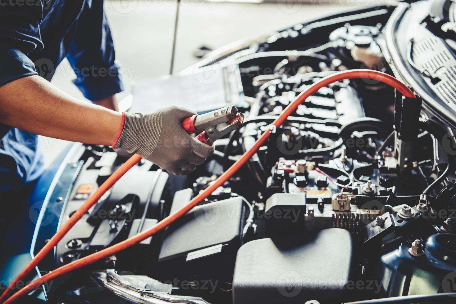 Car mechanic holding battery electricity trough cables jumper photo