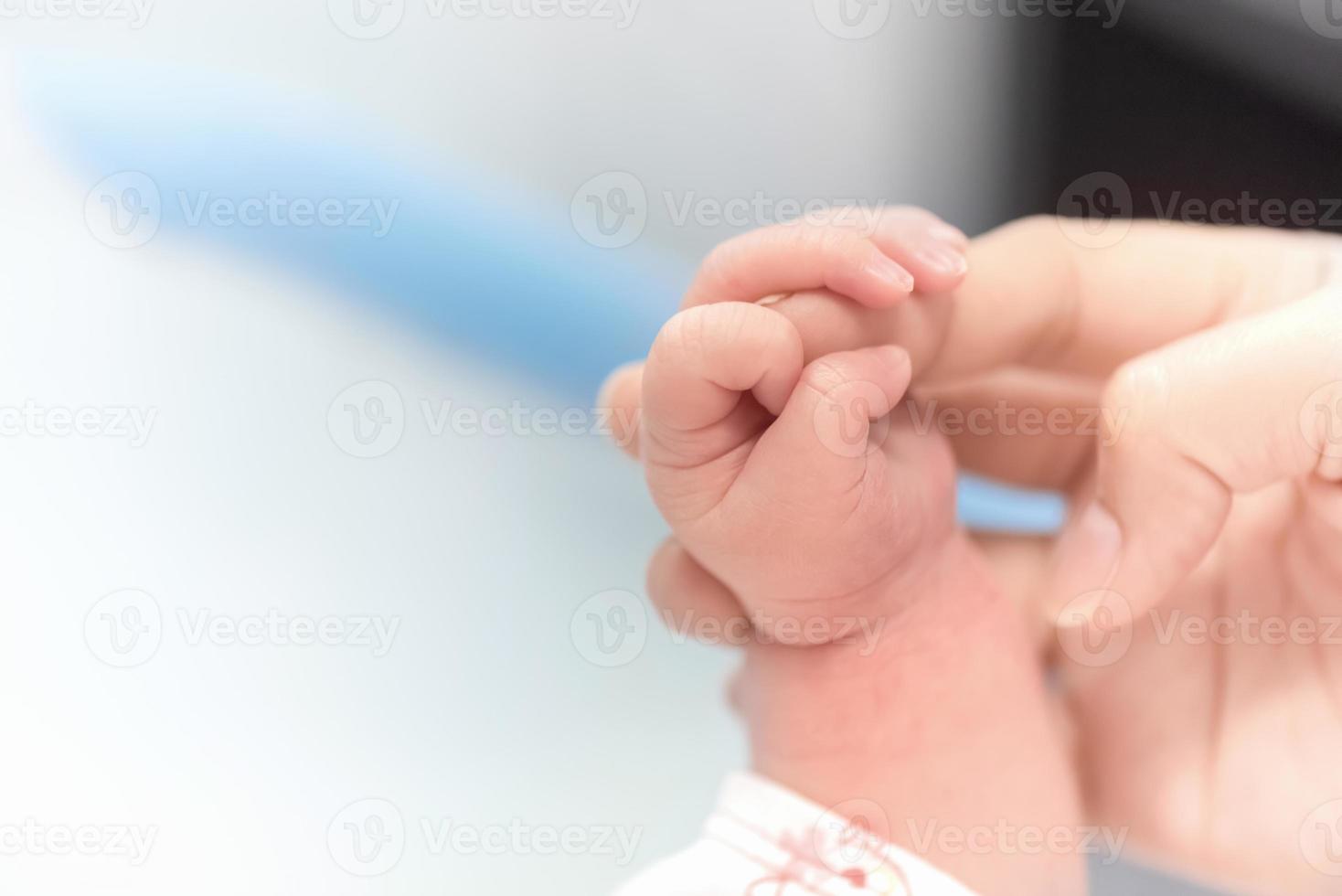 Newborn hand holding mother finger in hospital photo