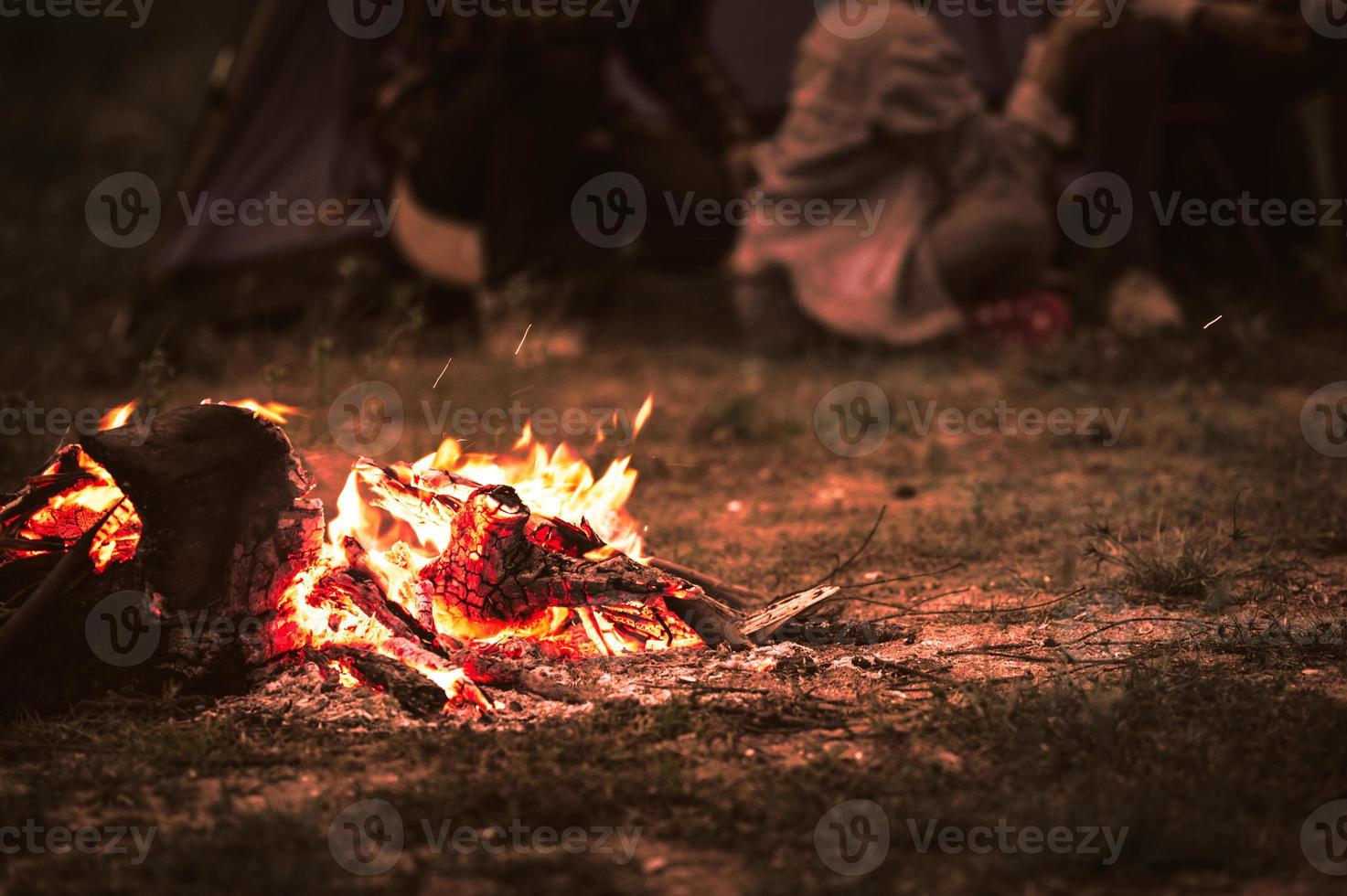 Encendiendo hoguera con turistas que se sientan alrededor de una hoguera brillante foto