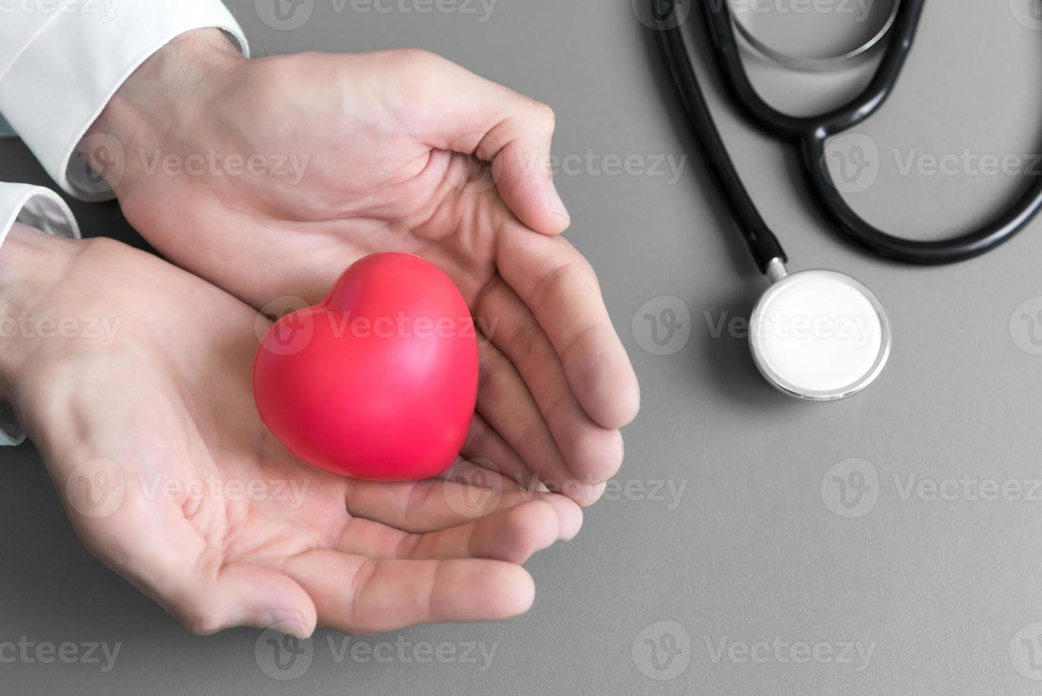 El médico sostiene las manos y le da un corazón de masaje rojo al paciente para que se recupere. foto