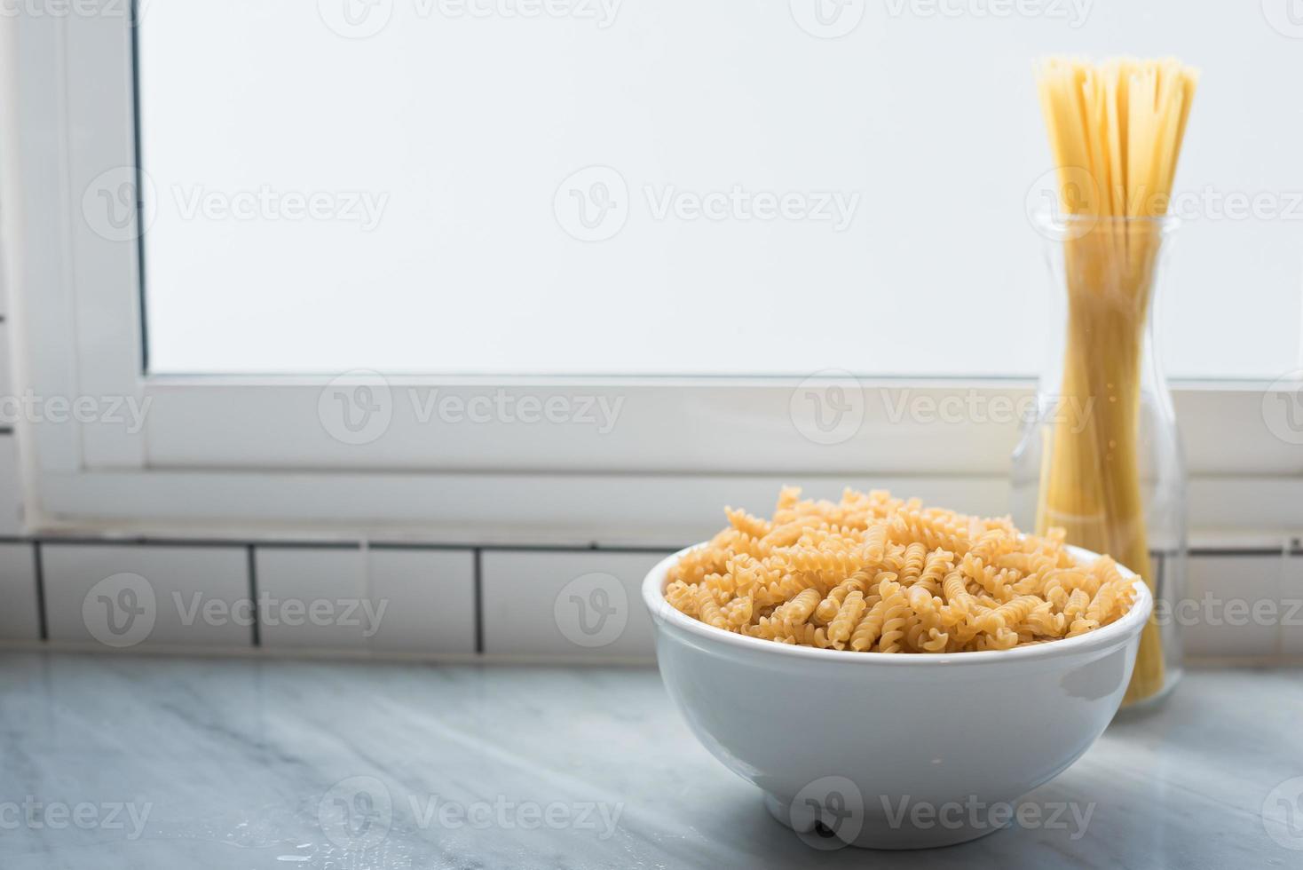 White bowl of spiral macaroni and tied spaghetti stand erect photo