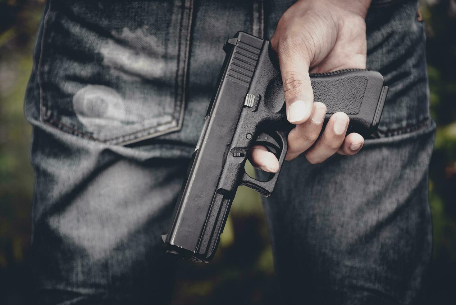 Close up of hand holding handgun in behind photo