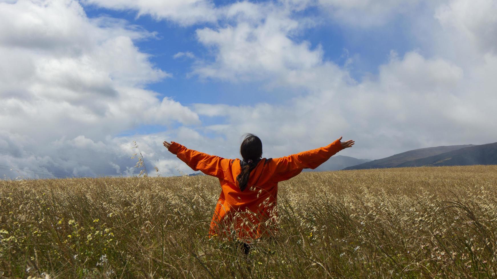 Young woman from behind raised arms looking at the sky photo