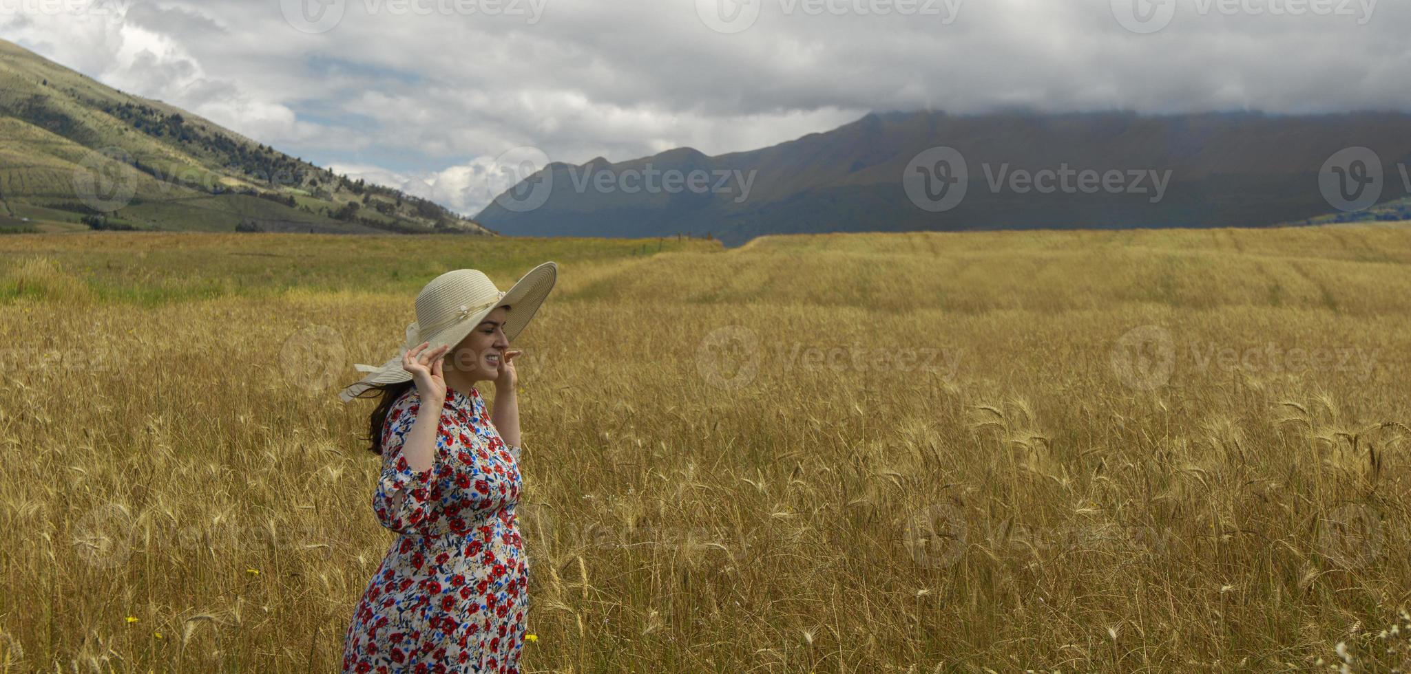 mujer en vestido floral sosteniendo su sombrero con sus manos caminando foto