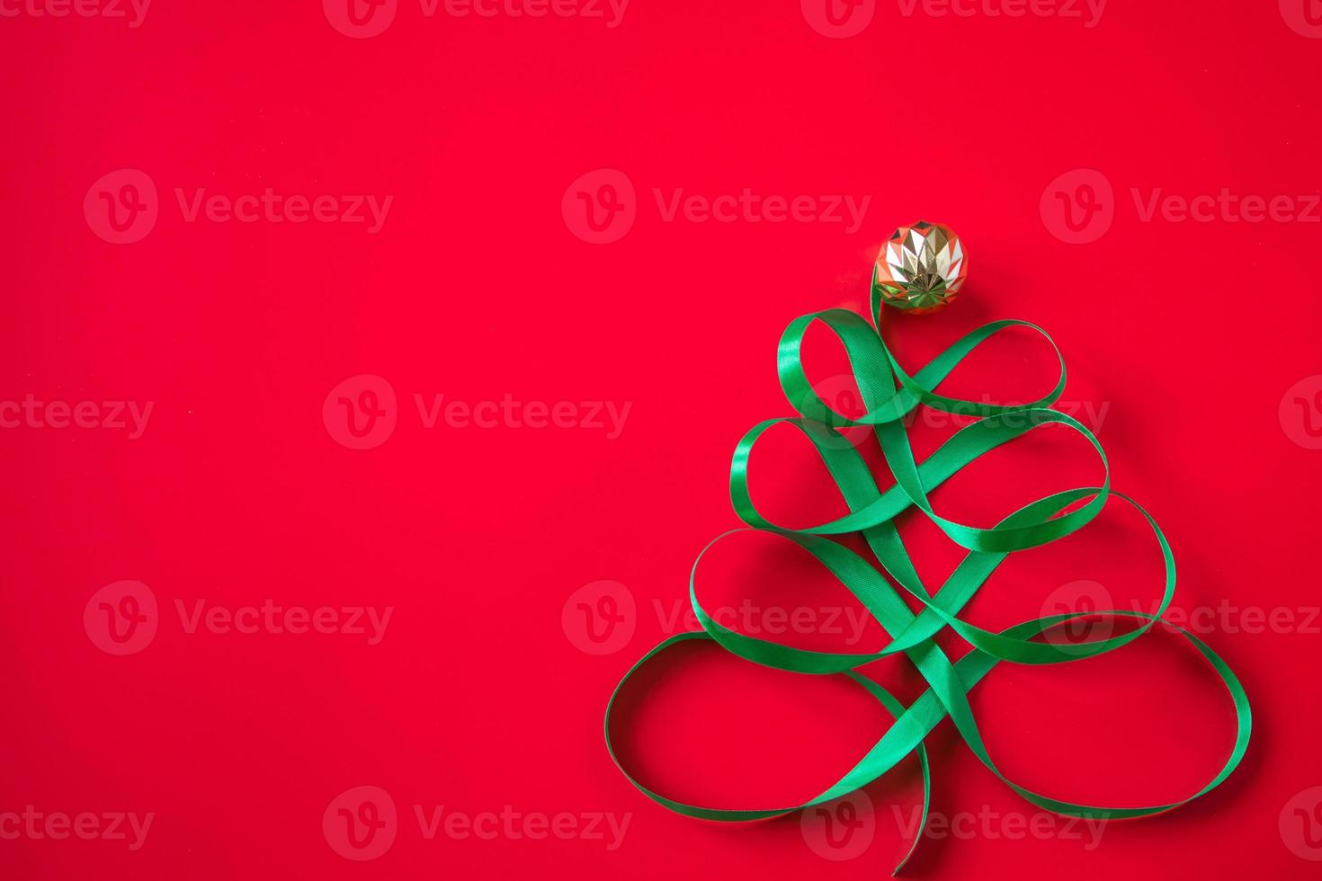 Festive tree made of green ribbon on red background. Christmas concept photo