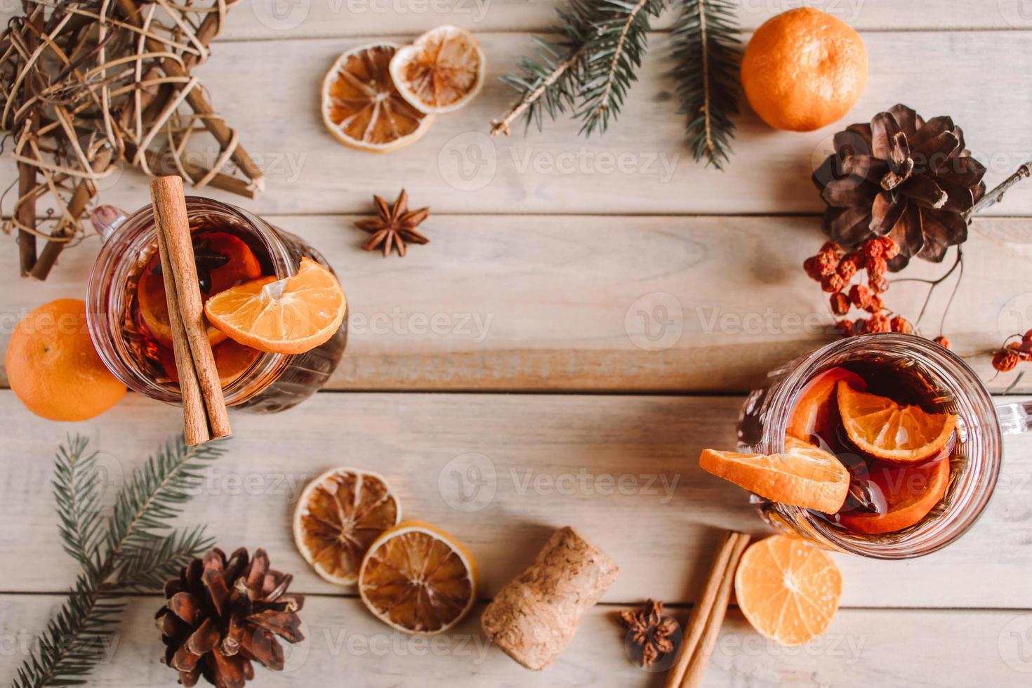 Hot mulled wine with fruits and spices on wooden background. photo