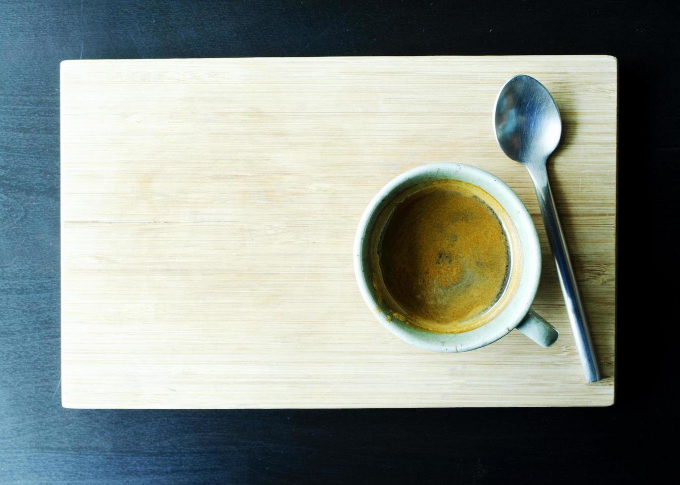 Tazas de café caliente y cuchara sobre fondos de placa de madera arriba foto