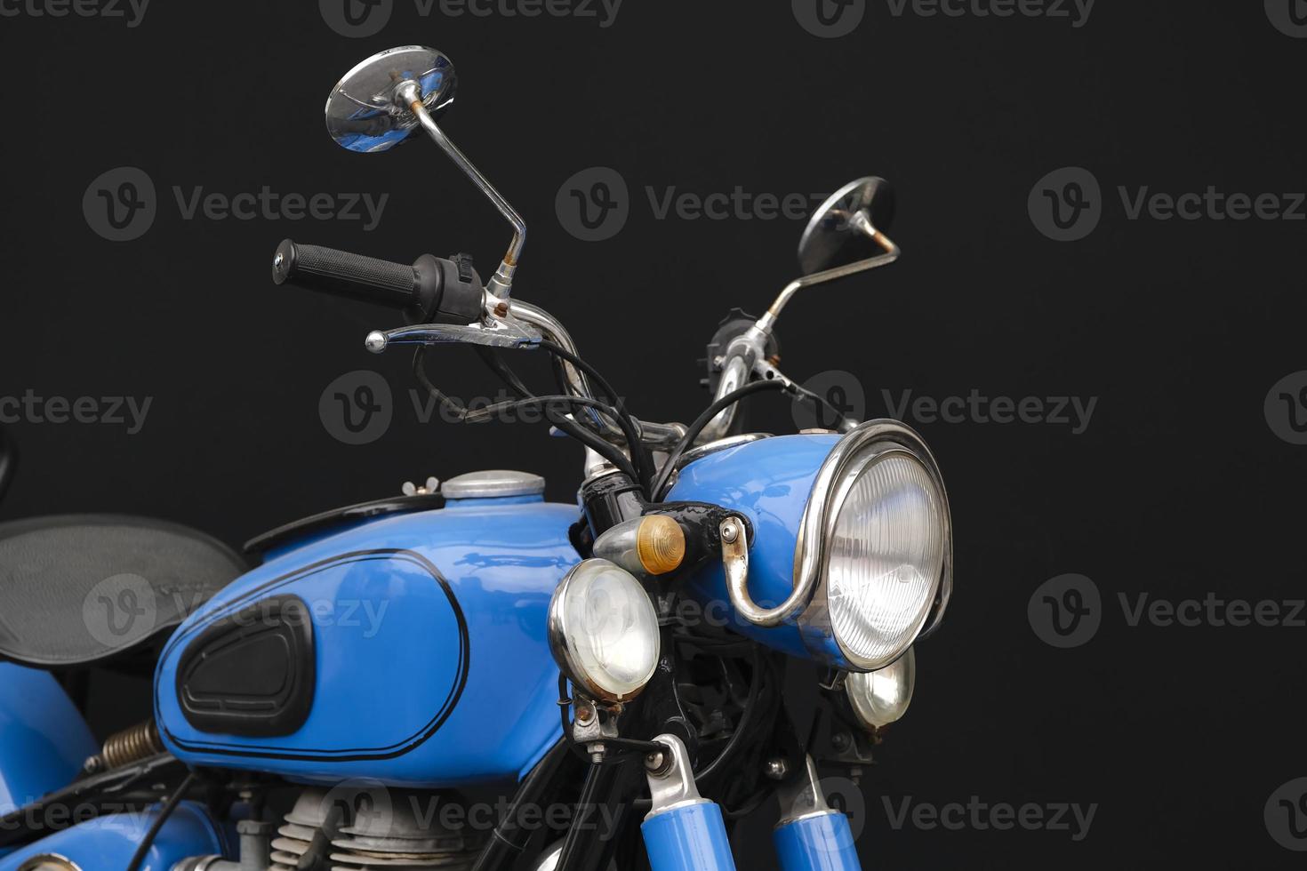 Closeup shot of a vintage blue motorcycle on black background photo