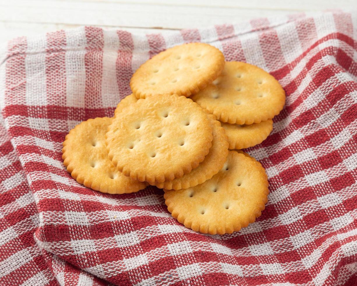 Galletas cracker con mantel sobre fondo de mesa de madera blanca foto