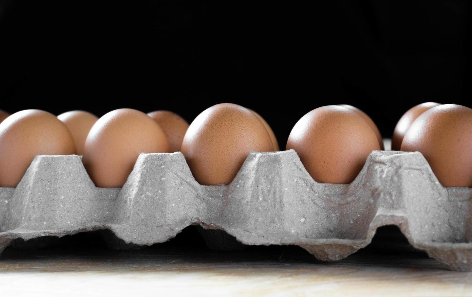 Huevos en paquete sobre mesa con fondo negro foto