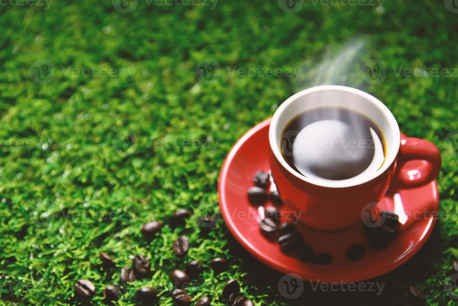 Taza de café rojo sobre la hierba verde con espacio de copia foto