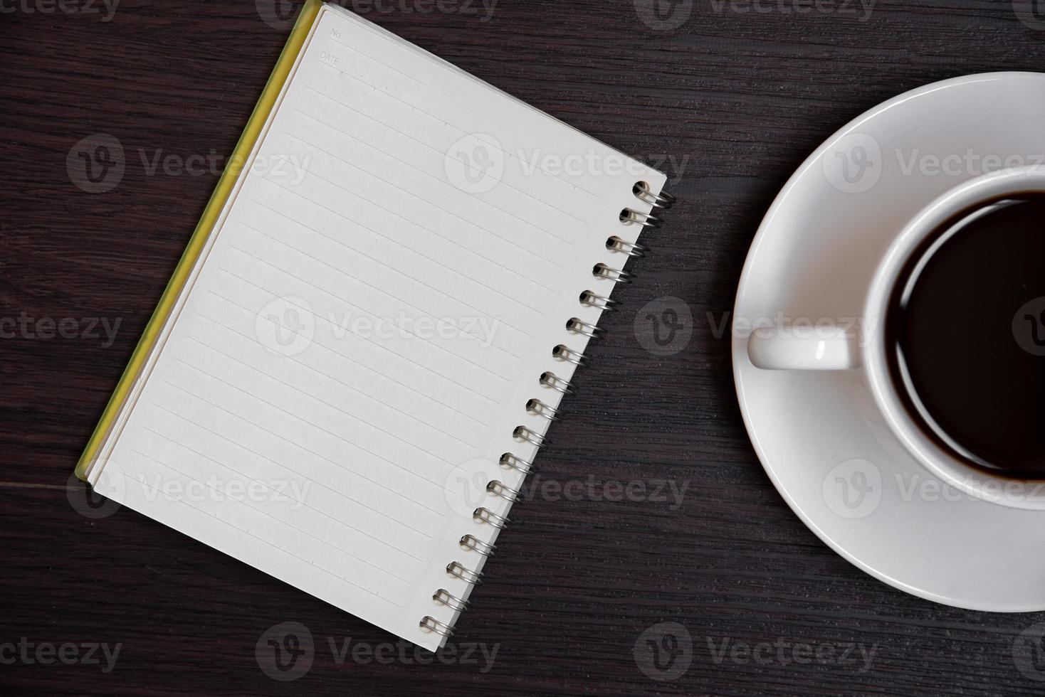 vista superior de la taza de café y el cuaderno en blanco para memo foto