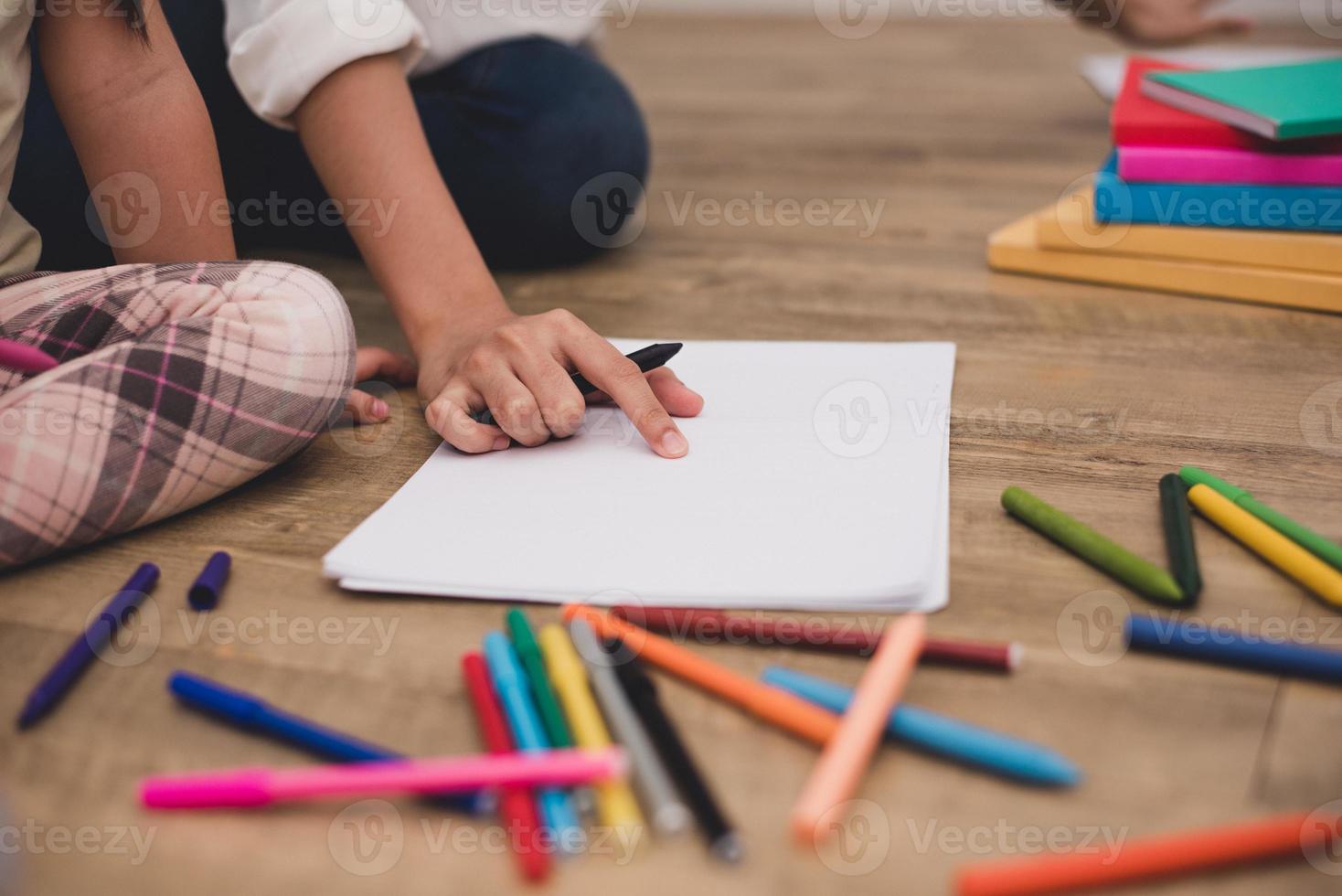 manos cerradas de mamá enseñando a los niños pequeños a dibujar una clase de arte foto