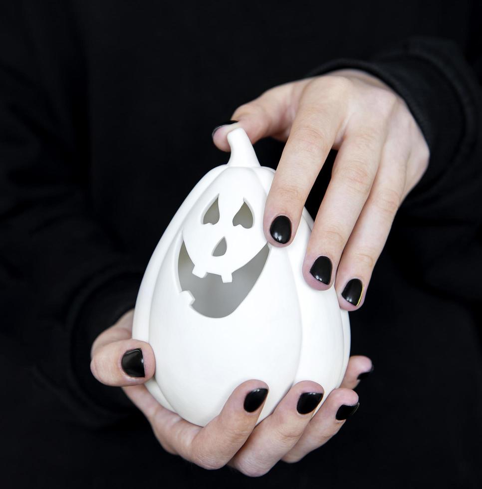 Female hands holding funny pumpkins on black background photo