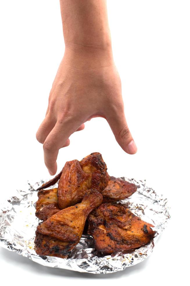 mano cogiendo ala asada. delicioso pollo a la parrilla en papel de aluminio foto