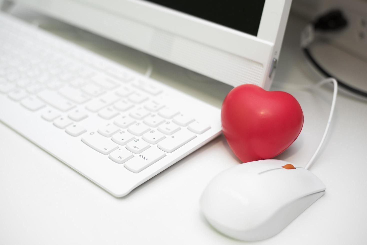 corazón rojo en la oficina con escritorio de computadora foto