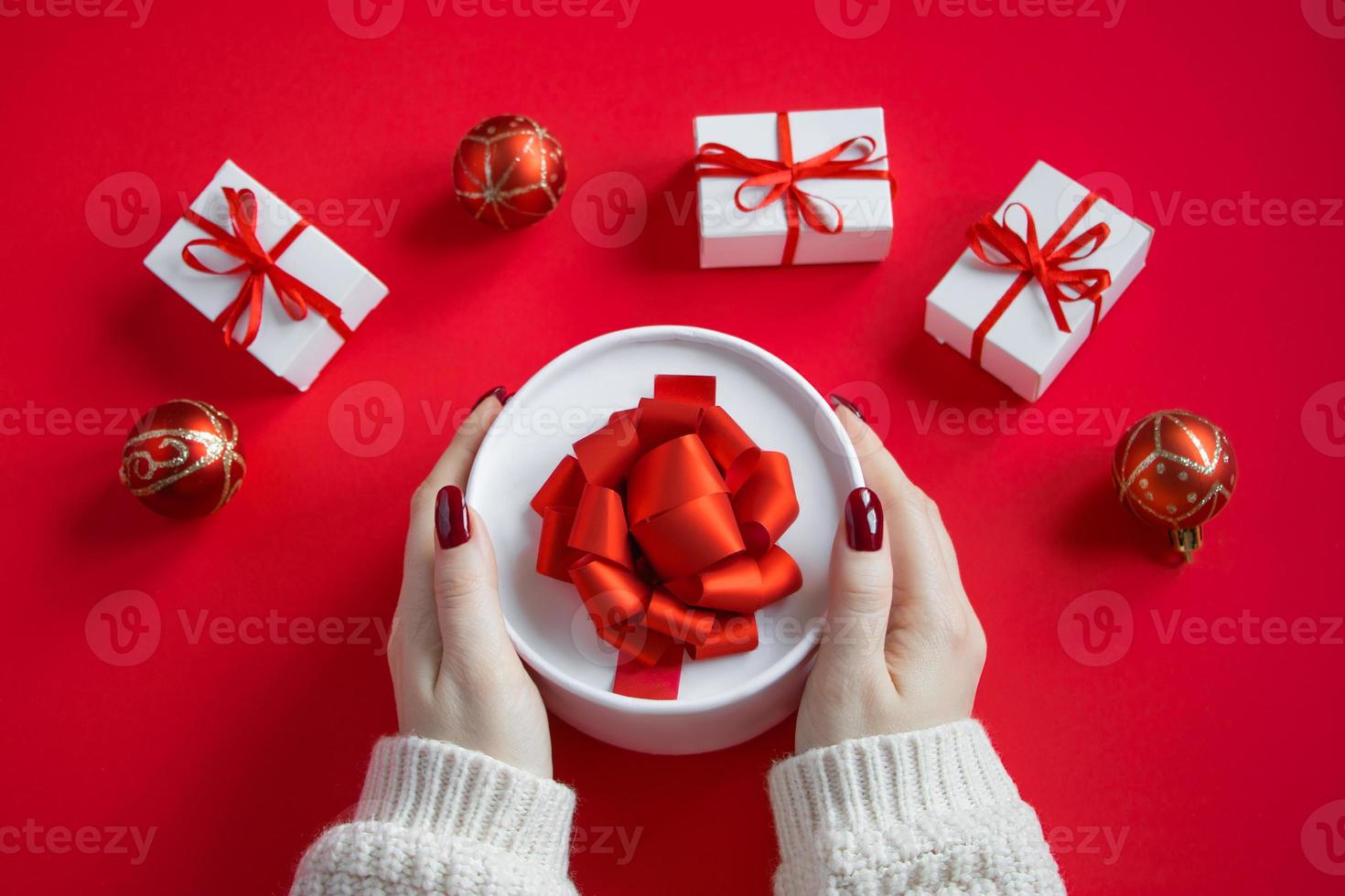 Hands hold beautiful gift box with bow on red background. photo