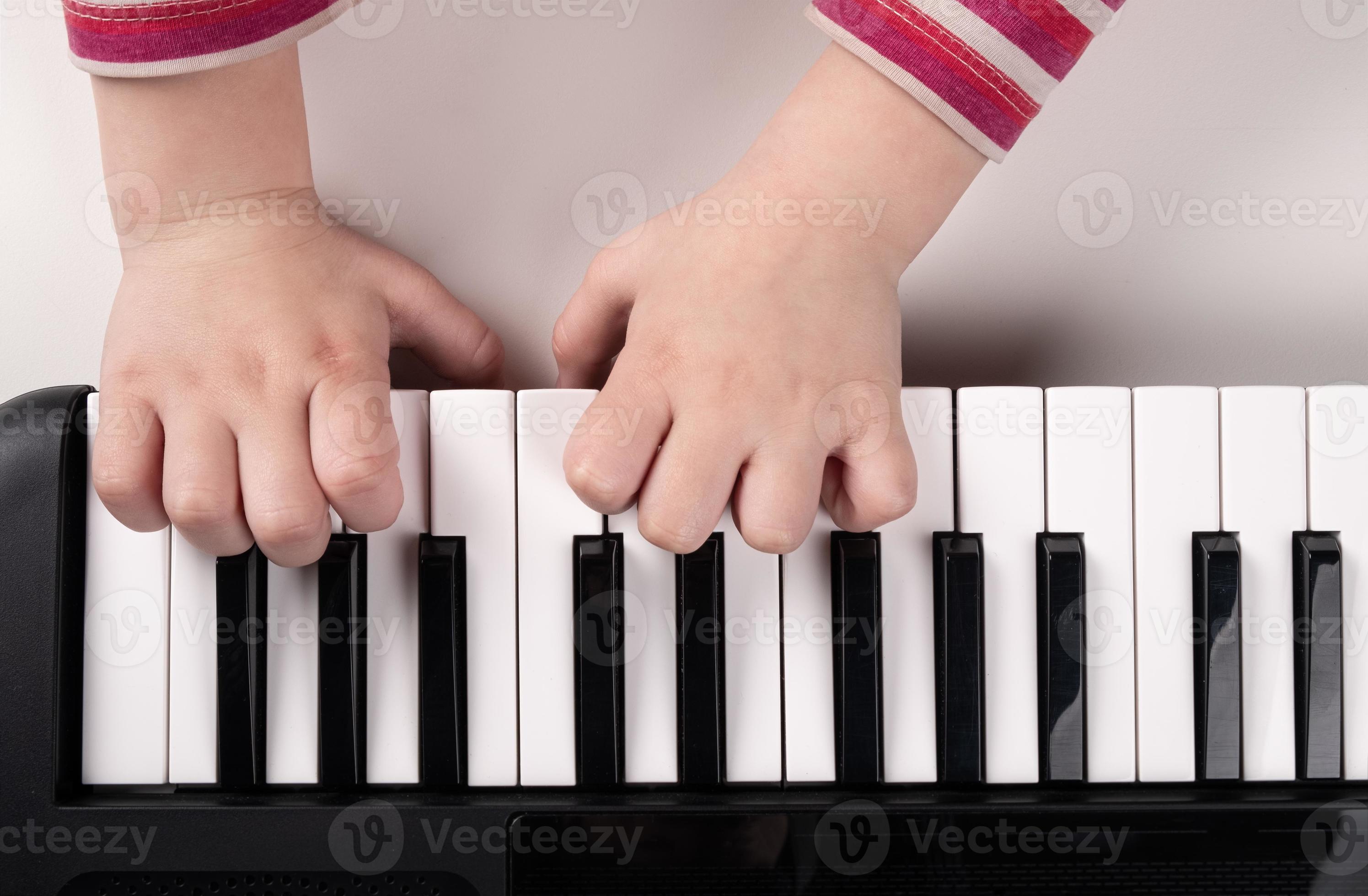 little kids hands playing piano top view, education concept photo