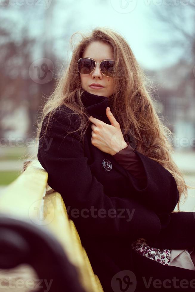 mujer elegante, en, gafas de sol, en el banquillo foto