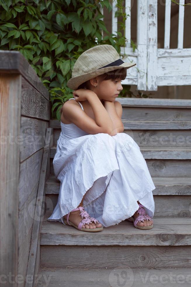 Sad little girl sitting alone photo