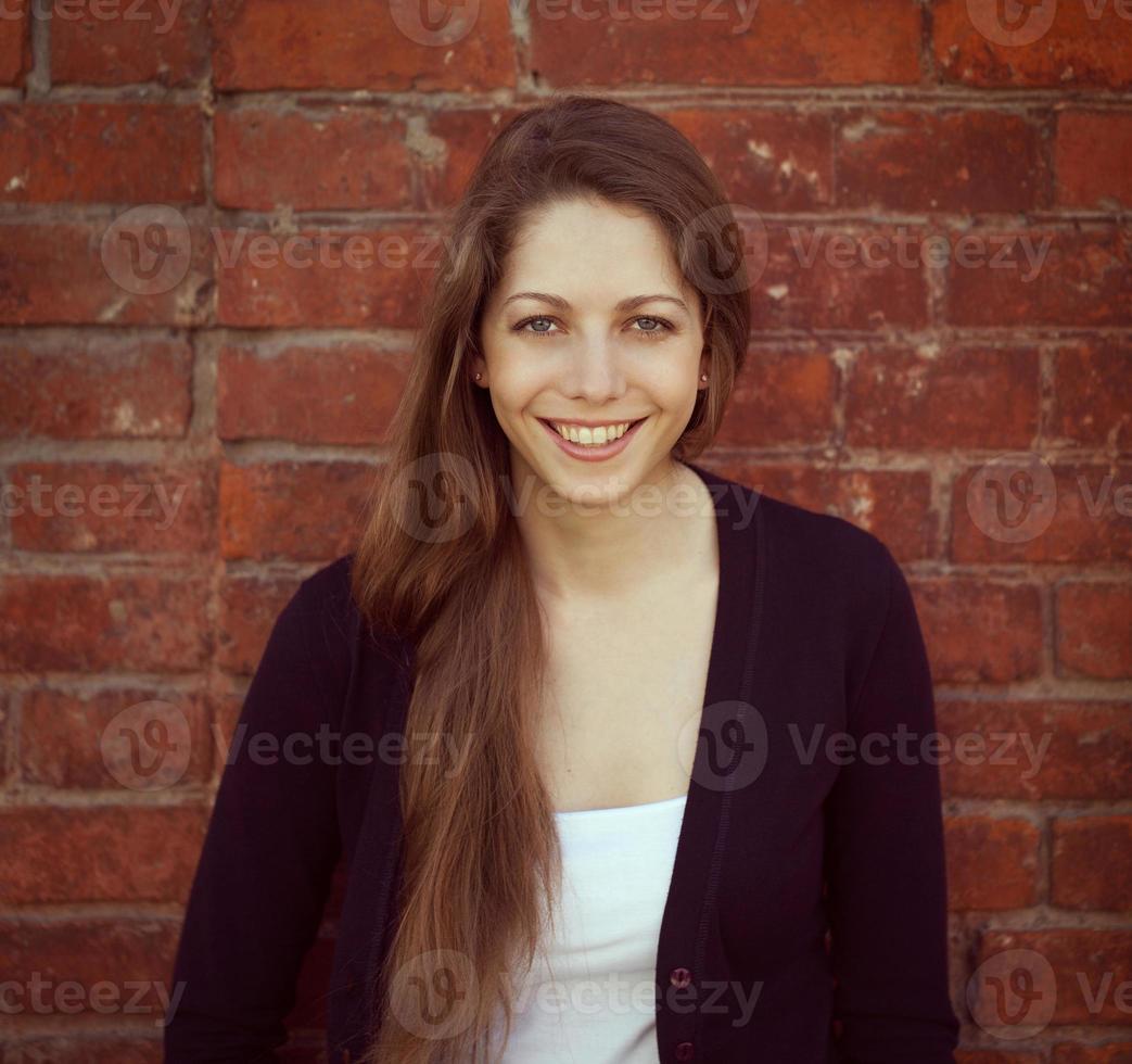 Beautiful long-haired girl at a wall photo