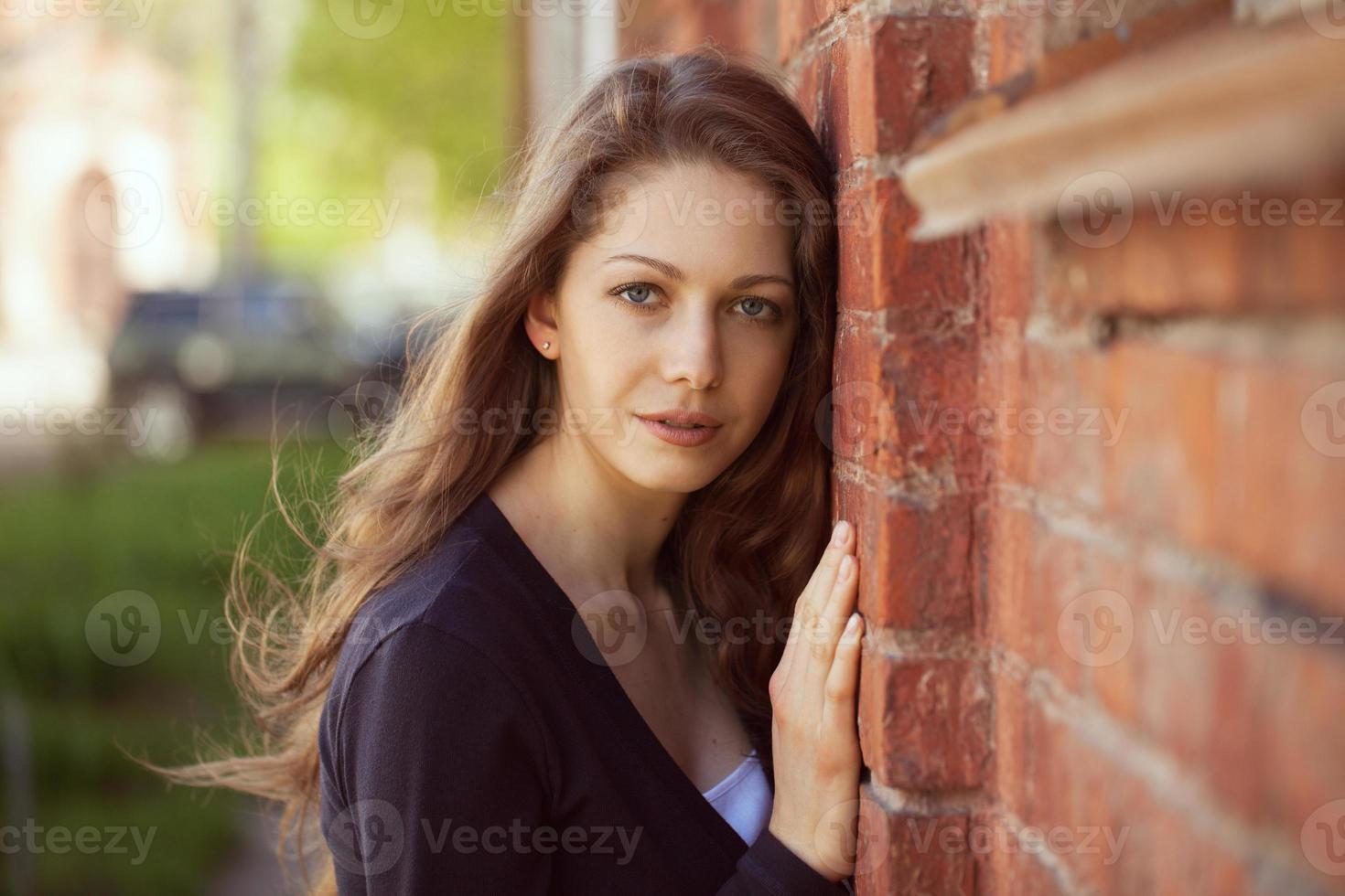 Beautiful woman near a brick wall photo