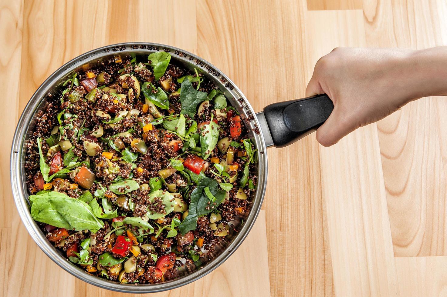 Hands holding a pot with a quinoa stew photo